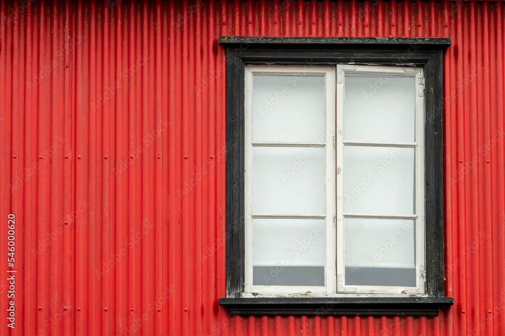 Window on a red painted wall, colorful house, architecture detail in Reykjavik, Iceland