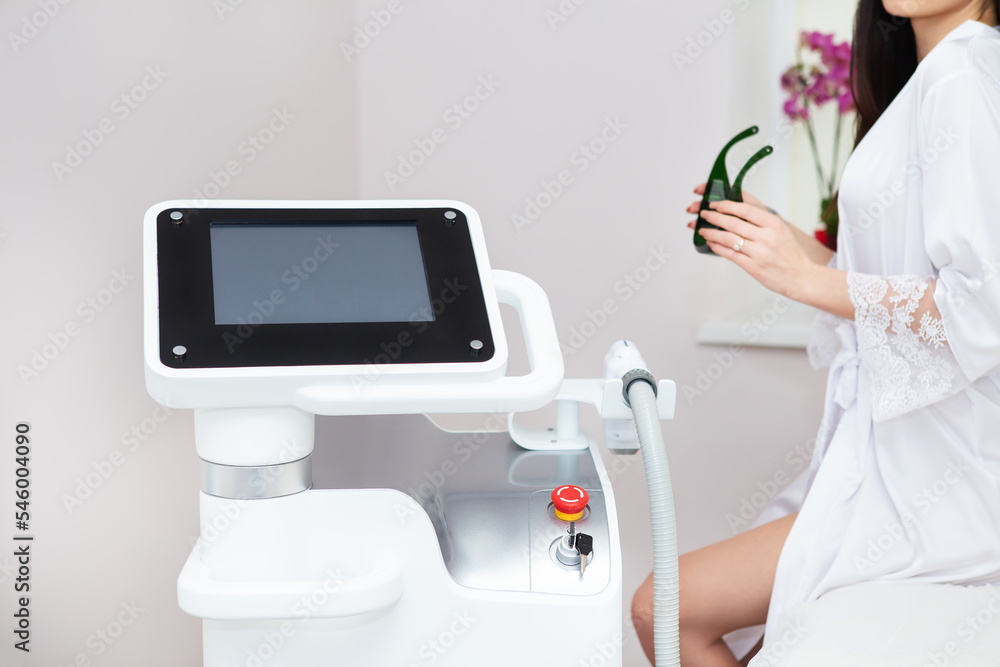 Professional laser hair removal machine, screen for setting up the hair removal process. Professional cosmetology, body epilation. Body care concept, client in the background. Professional laser hair removal machine, screen for setting up the hair removal process. Professional cosmetology, body epilation. Body care concept, client in the background.