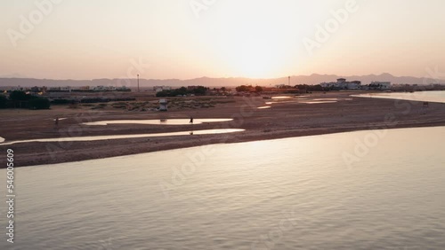 Aerial shot of a person walking along the coast of a beach during a beautiful sunset in Egypt