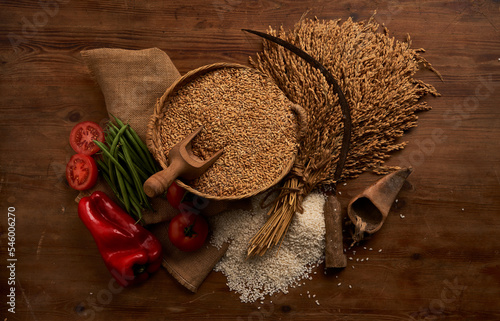 Wooden bowl of wheat corns and sickle