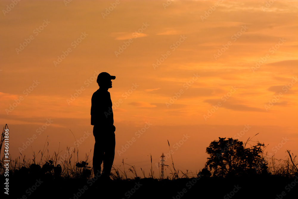 Man silhouette stand alone on the fields during sunset. Beautiful moment. Man reaching outdoor enjoying freedom.