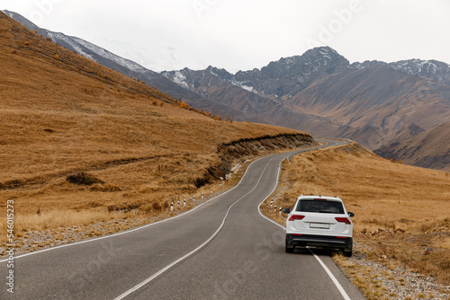 White car stands on the side of the road in the mountains in autumn