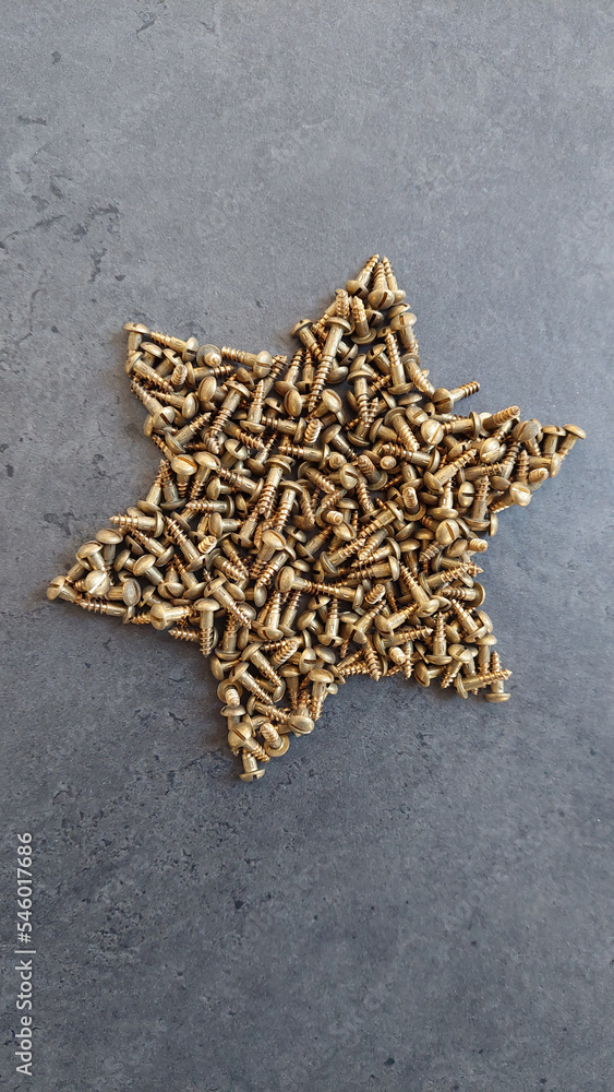 Weihnachtsstern gelegt aus Messingschrauben auf schwarzem Hintergrund Weihnachtsstern gelegt aus Messingschrauben auf schwarzem Hintergrund