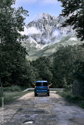 small van driving along a narrow and lonely road with one hand sticking out the left window and the other hand sticking out the right window, ruta del cares asturias, spain