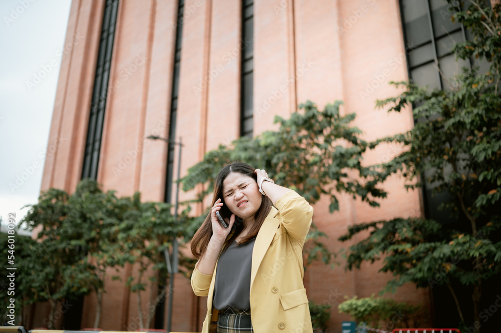 Young Asian woman using her phone to chat and send messages outdoors , Talking on the phone, headache with customers .Concept of business and communication Young Asian woman using her phone to chat and send messages outdoors , Talking on the phone, headache with customers .Concept of business and communication