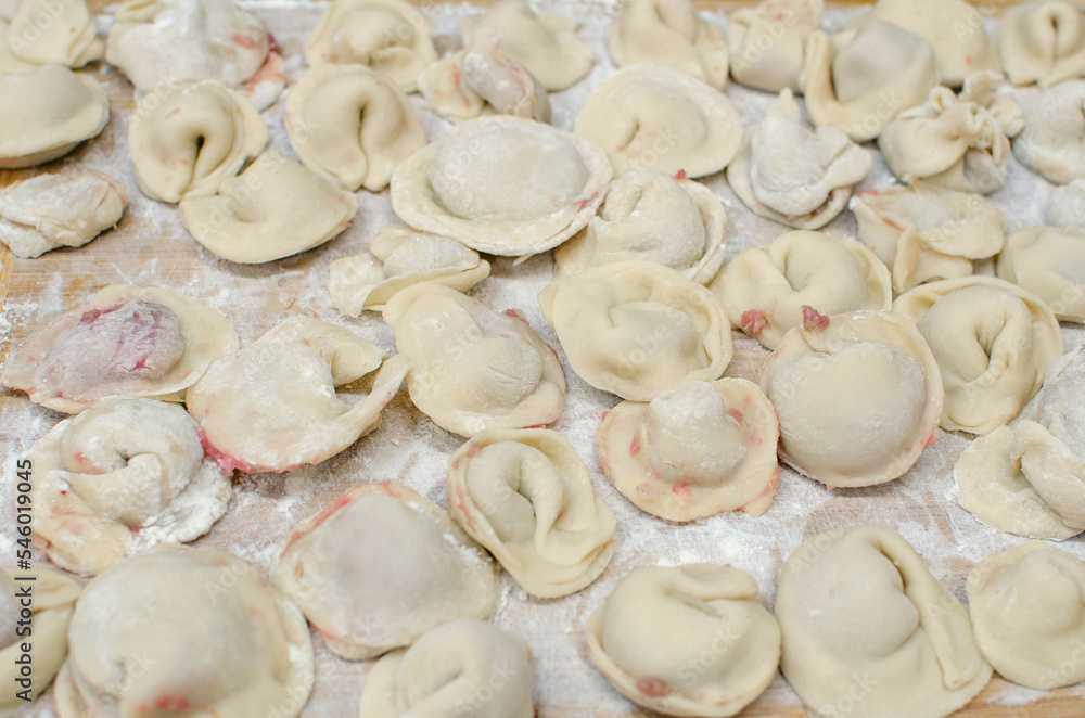 Process of making homemade raw pastry dumplings with meat filling on a wooden Board. Pelmeni. A traditional dish of Russian cuisine. Selective focus Process of making homemade raw pastry dumplings with meat filling on a wooden Board. Pelmeni. A traditional dish of Russian cuisine. Selective focus