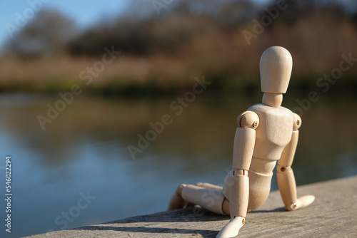 Принти на полотні A wooden mannequin doll sits on a river bridge. Copy space.