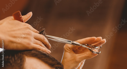Barber shop concept, male hairdresser cutting hair with scissors, brown tinting vintage color