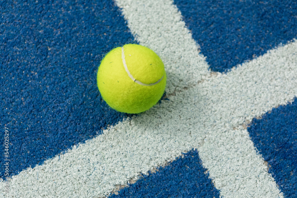 Tennis ball in a blue floor in a panel court