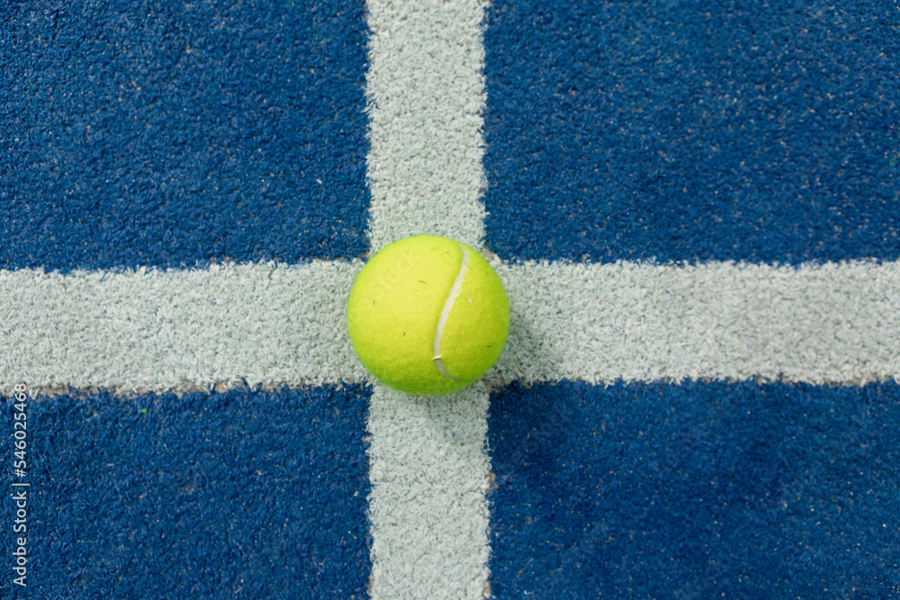 Tennis ball in a blue floor in a panel court