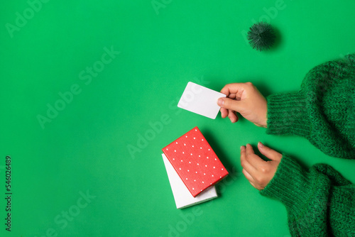 Female hands holding bonus or credit bank card template for paying for purchase of gifts in boxes