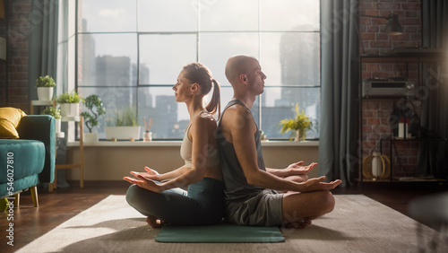 Young Athletic Couple Exercising, Practising Meditation in the Morning in Her Bright Sunny Home Living Room. Healthy Lifestyle, Fitness, Wellbeing and Mindfulness Practice Concept.