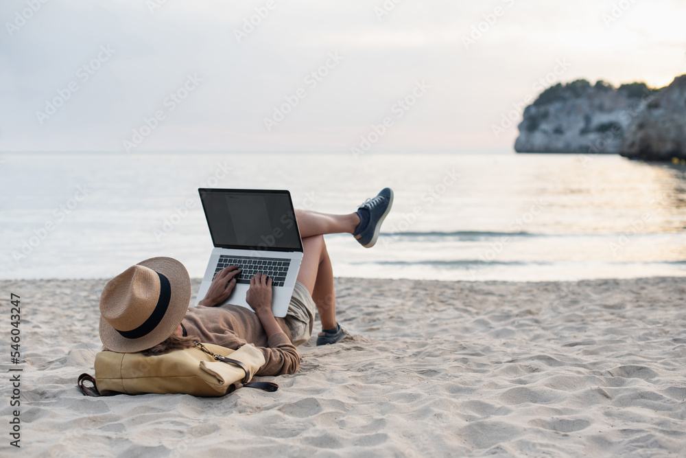 Young woman using laptop computer on beach, freelancer girl working remote, Freelance work, online learning, distant work, connection concept	