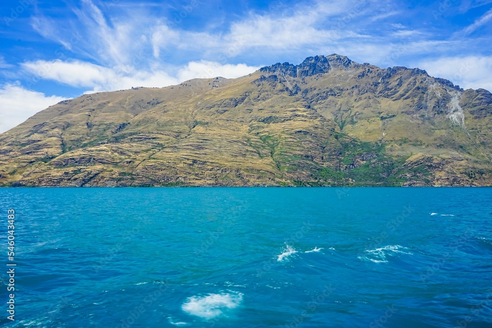Sea surrounding the island with high rocky mountains with blue sky in the background