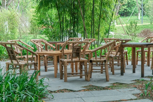 Wooden chairs and tables in a seat area next to the trees in a park
