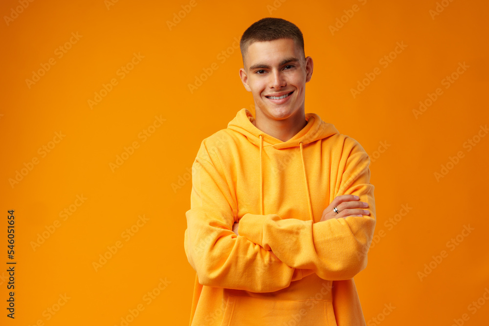 Happy smiling young man looking to camera over yellow background Happy smiling young man looking to camera over yellow background