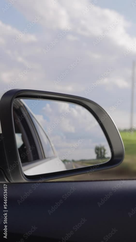 Vertical Video, View from of the Side Mirror the Inside of a Driving Car Along the Highway in a Sunny Day. Concept of Vehicles and Transport. No People. Vertical Video, View from of the Side Mirror the Inside of a Driving Car Along the Highway in a Sunny Day. Concept of Vehicles and Transport. No People.
