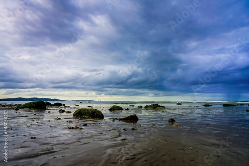 View of the rocky shore against the background of the stormy cloudscape.