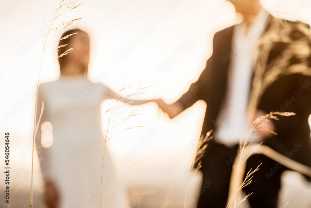 Φωτογραφία Pareja de recién casados dandose la mano en puesta de sol desenfocados