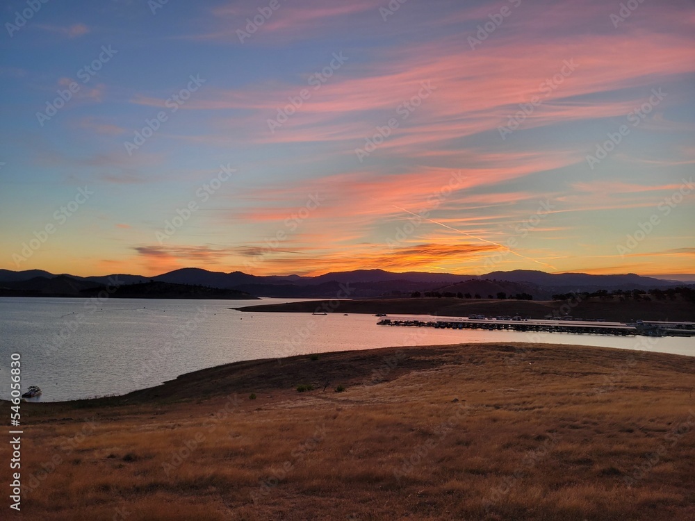 Scenic view of a lake against distant mountains at a pink sunset