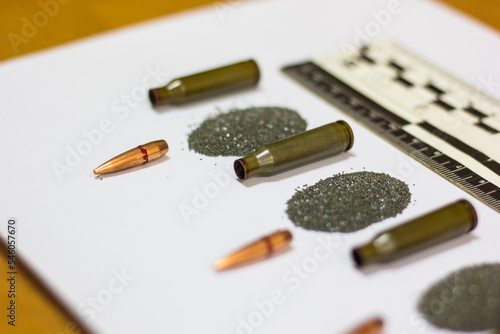 Bullet, cartridge case, cartridge, forensic ruler on a sheet of white paper