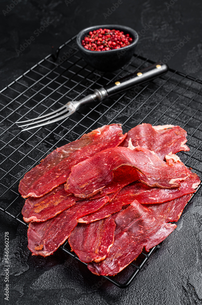 Dried sliced basturma, cured beef meat ready for eat. Black background. Top view
