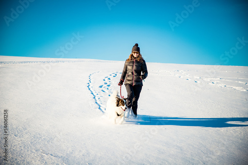 woman and her happy white dog enjoying winter snow outdoors on sunny day