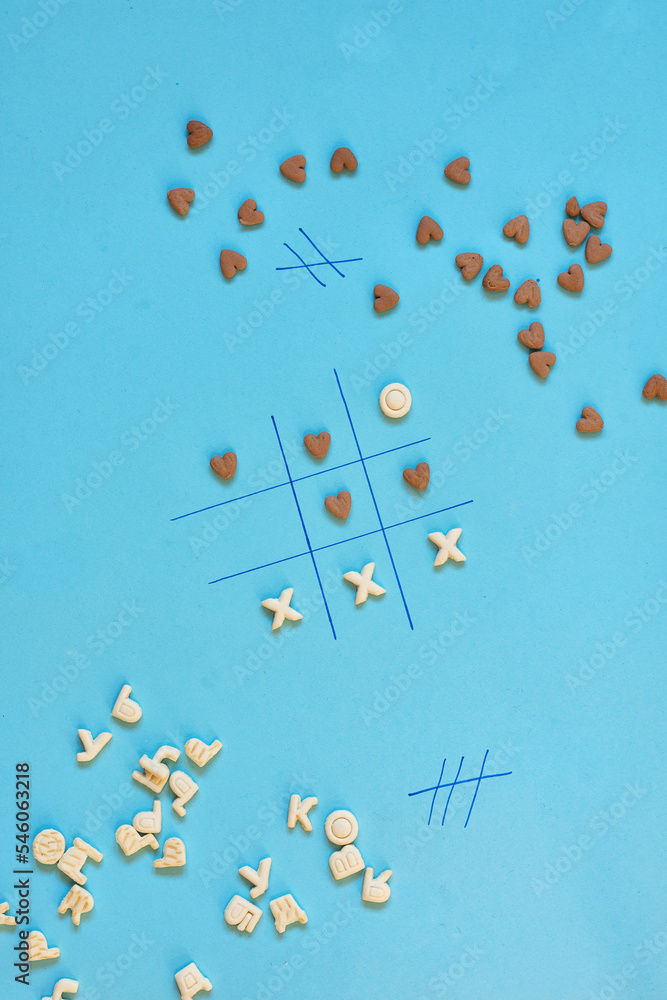 A cracker board game where letters play against chocolate cracker hearts. Funny food game. Creative flat lay concept.