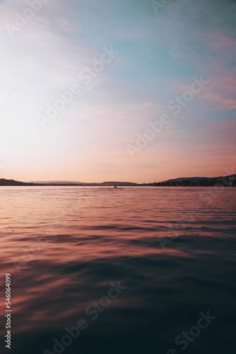 Vertical shot of a seascape at sunset with hills in the background