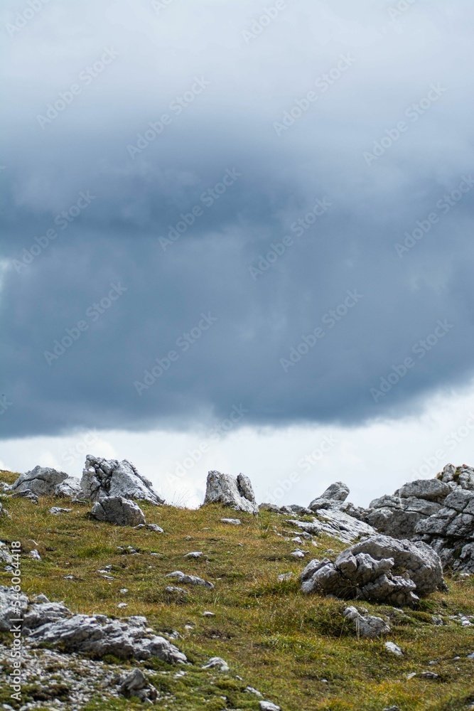 Vertical shot of the rocky meadow against the background of the cloudy sky.