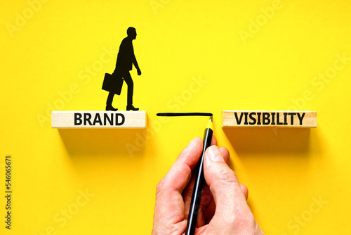 Brand visibility symbol. Concept words Brand visibility on wooden blocks. Beautiful yellow table yellow background. Businessman hand. Business branding and brand visibility concept. Copy space.