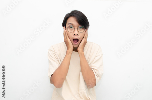 ecstatic attractive young asian man shocked happily opening mouth and lowering glasses. asian man with glasses feels shock with wow surprised expression.