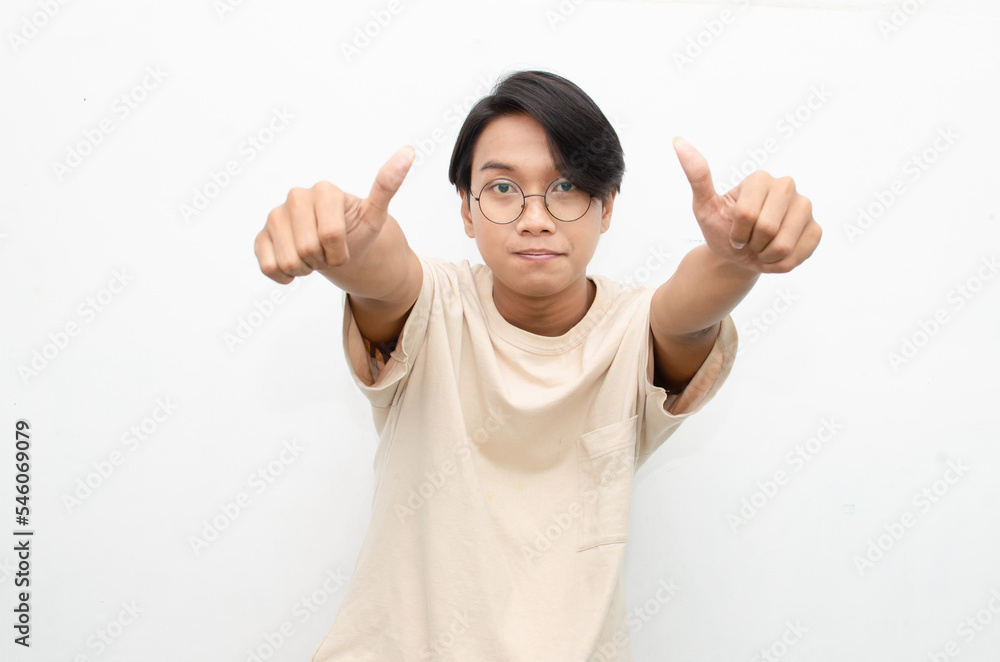 handsome attractive Asian man smiling happily and giving thumbs up as compliment isolated over white background. man giving approval and compliment by gesturing thumbs up. handsome attractive Asian man smiling happily and giving thumbs up as compliment isolated over white background. man giving approval and compliment by gesturing thumbs up.