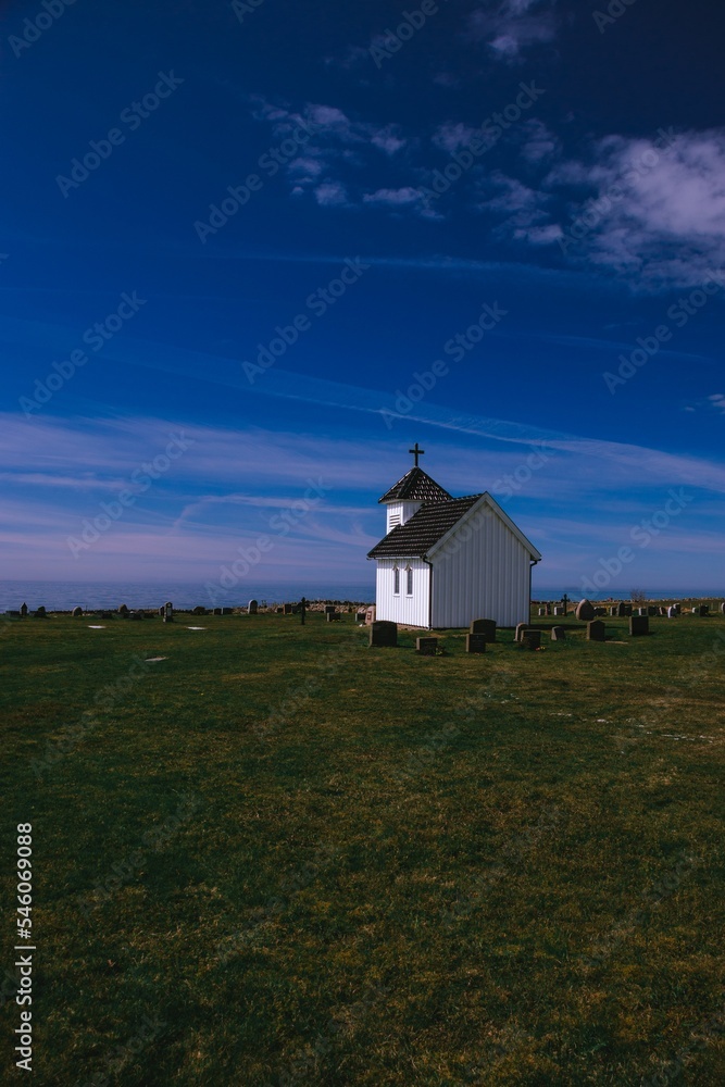 Vertical shot of an old village church and graveyard on a sunny day in Varhaug Vertical shot of an old village church and graveyard on a sunny day in Varhaug