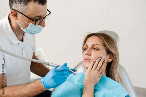 Attractive woman afraid of dentist. Dentist consults frightened girl in dentistry. Treatment of teeth and toothache in dentistry.