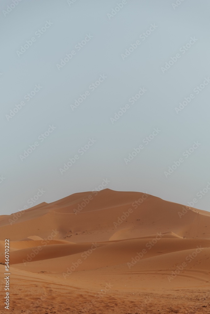 Orange sand Dunes in the desert with the light blue sky background