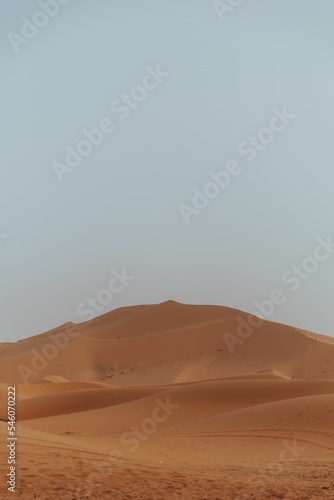 Orange sand Dunes in the desert with the light blue sky background