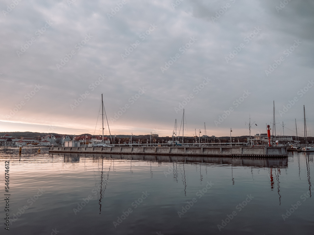 Pier in Sopot at sunrise time with amazing colorful sky. Many yachts and boats are moored at the pier. Poland. Europe. Vacation at sea. Selective focus.