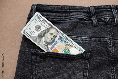 One hundred dollar bill sticking out of the pocket of black jeans