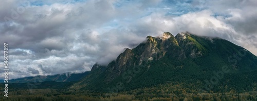 Fototapeta Naklejka Na Ścianę i Meble -  Panoramic view of lush green mountain tickling the white clouds in blue sky