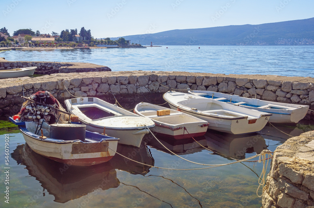 Beautiful autumn Mediterranean landscape. Fishing boats at small stone jetty. Montenegro, Adriatic Sea, view of Bay of Kotor near Tivat city