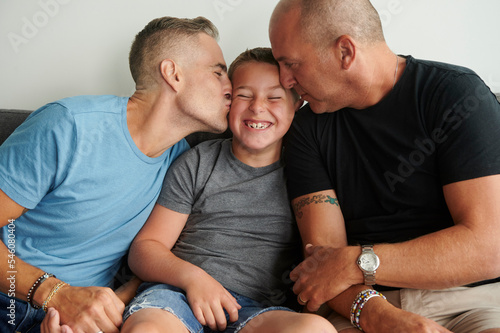 Same sex male couple kissing their son.