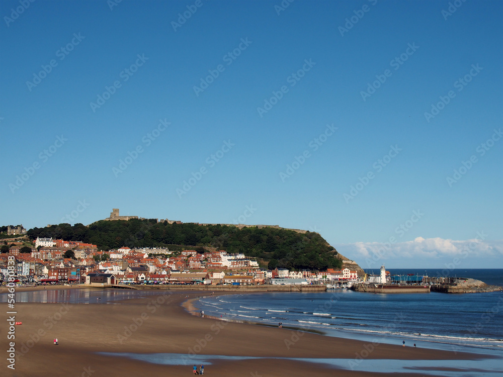 view of scarborough south bay with beach and town on a sunlit summer day with the harbour and castle in the distance