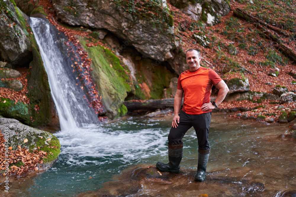 Athletic mature man hiker by a waterfall