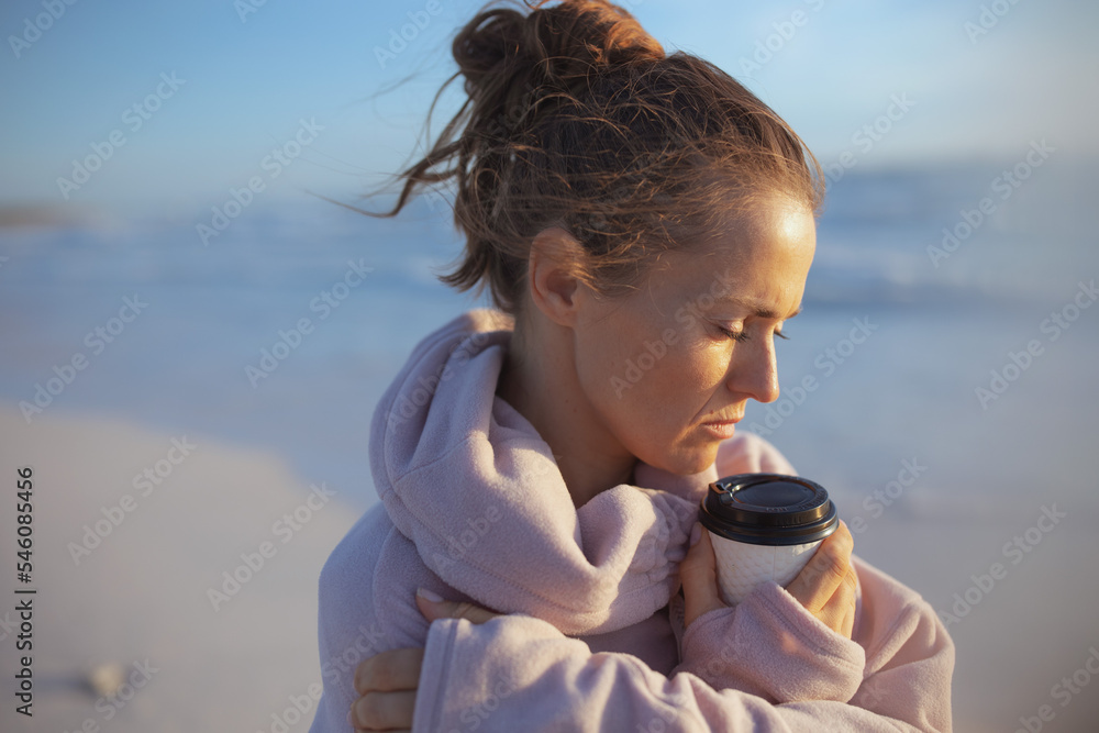 stressed stylish woman in cosy sweater at beach in evening