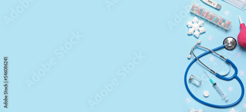 Supplies of doctor with Christmas decorations on light blue background with space for text