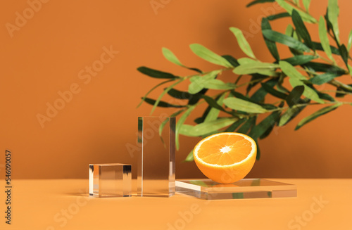 Front view mockup empty glass stage for cosmetic product presentation on natural background with olive tree branch and orange slice.