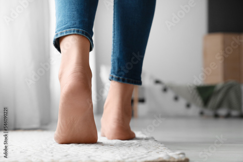 Female bare feet on rug in room, closeup