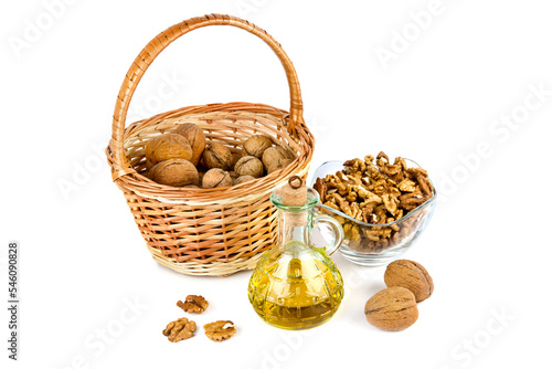 Walnuts in a basket and natural walnut oil isolated on white .