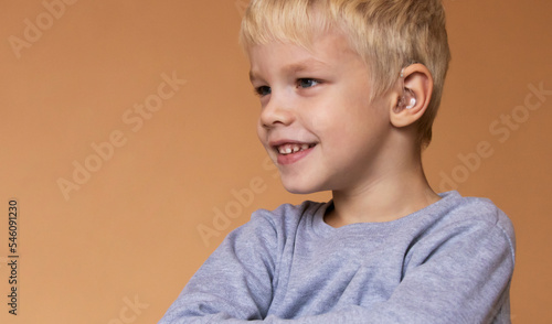 A boy with a hearing aids on beige background
